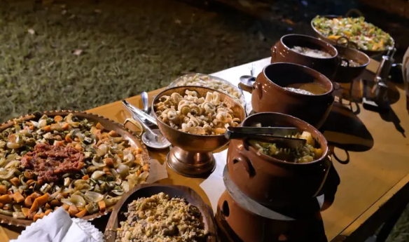 Mesa de buffet com acompanhamentos servidos em panelas