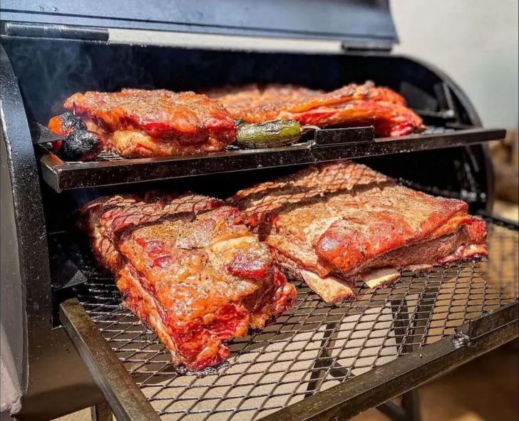Costelas e cortes bovinos assando no pit smoker