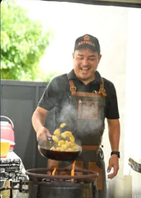 Diego Brandini cozinhando na chapa durante um evento